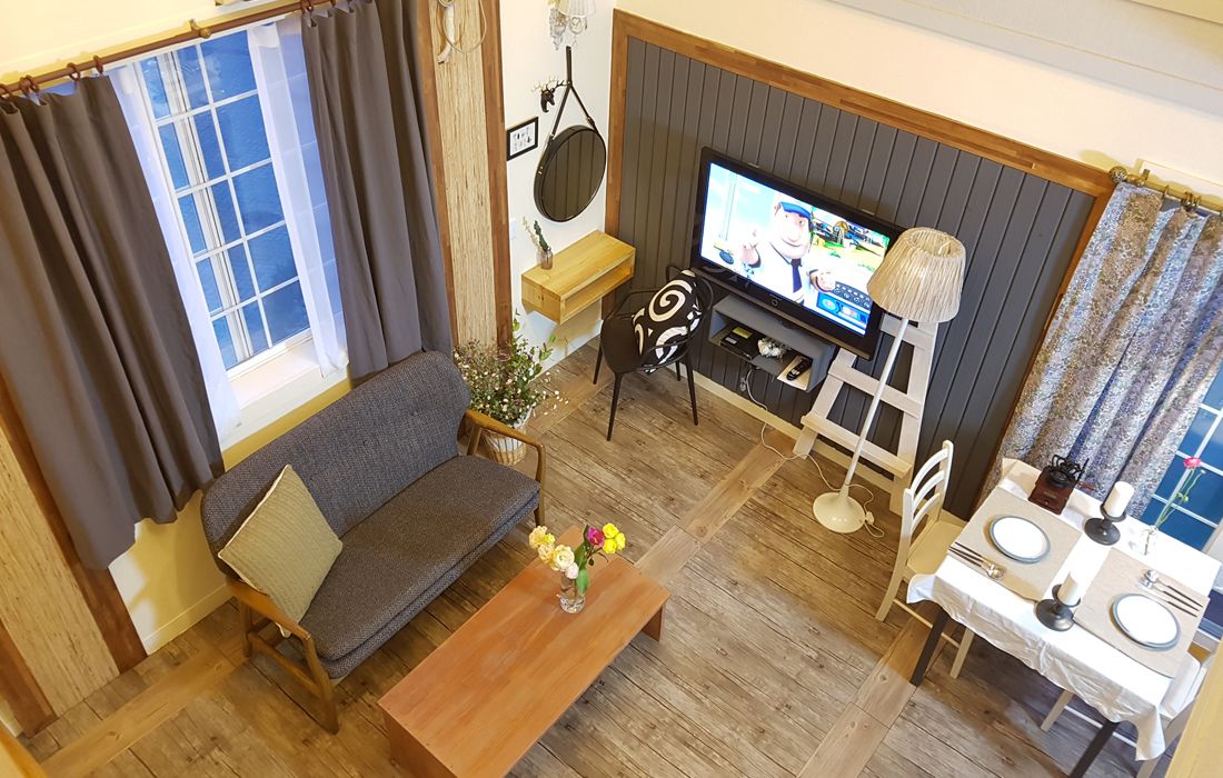 A living room with a sofa, coffee table, TV, and dining area.
