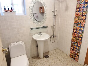 Une salle de bain équipée de toilettes, d’un lavabo, d’une douche et d’un rideau de douche décoratif à motifs de cœurs.