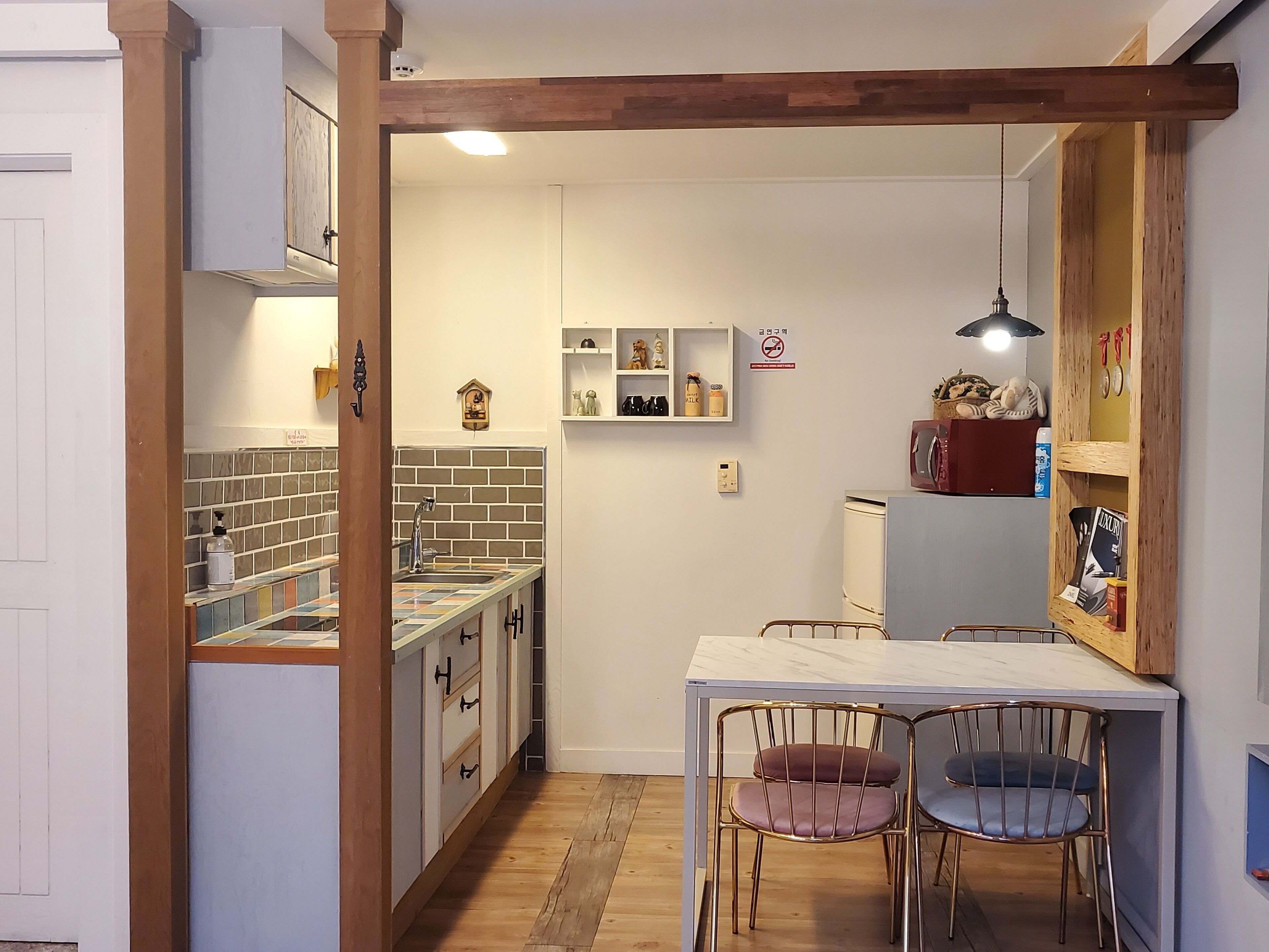 Una cocina compacta con salpicadero de azulejos, armarios de madera y encimera de mármol, además de un comedor con dos sillas.
