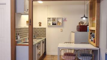 Una cocina compacta con salpicadero de azulejos, armarios de madera y encimera de mármol, además de un comedor con dos sillas.