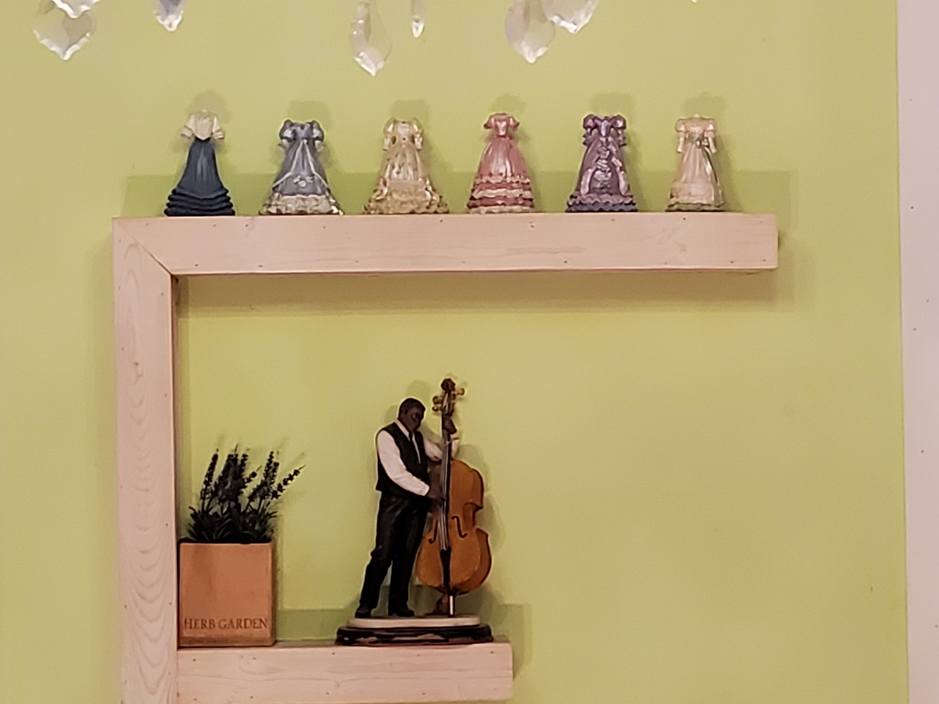 A shelf with decorative items and a figurine of a man playing a cello.