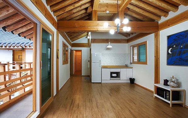 A spacious kitchen with wooden beams, a refrigerator, and a sink.
