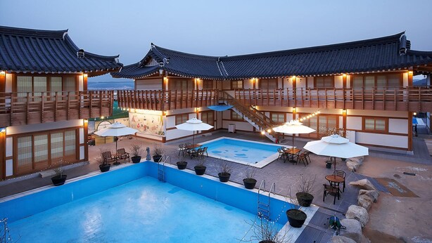 Un edificio de estilo tradicional japonés con piscina, asientos al aire libre y una escalera.