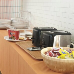 A kitchen counter with a toaster, a bowl of snacks, a red cup, and a clear plastic container. - Gyeongju N Hanok Pension (Gyeongju)