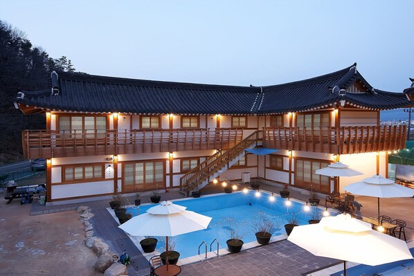 A traditional Japanese-style building with a swimming pool, outdoor seating, and a staircase leading to the upper floor. - Gyeongju N Hanok Pension (Gyeongju)