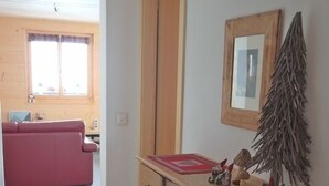 A room with a wooden cabinet, a mirror, and a small Christmas tree decoration. - Appartement Moilles 15 (Val d'Illiez)