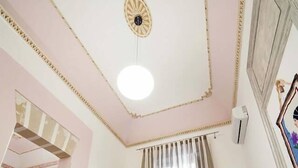 A hotel room with a bed, a ceiling fan, a window with curtains, and a wall-mounted air conditioner. - Belle Epoque B&B (Trapani)