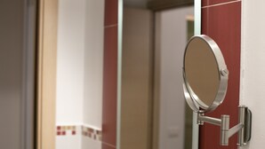 A bathroom with a mirror mounted on a wall, a door, and a tiled floor. - Belle Epoque B&B (Trapani)