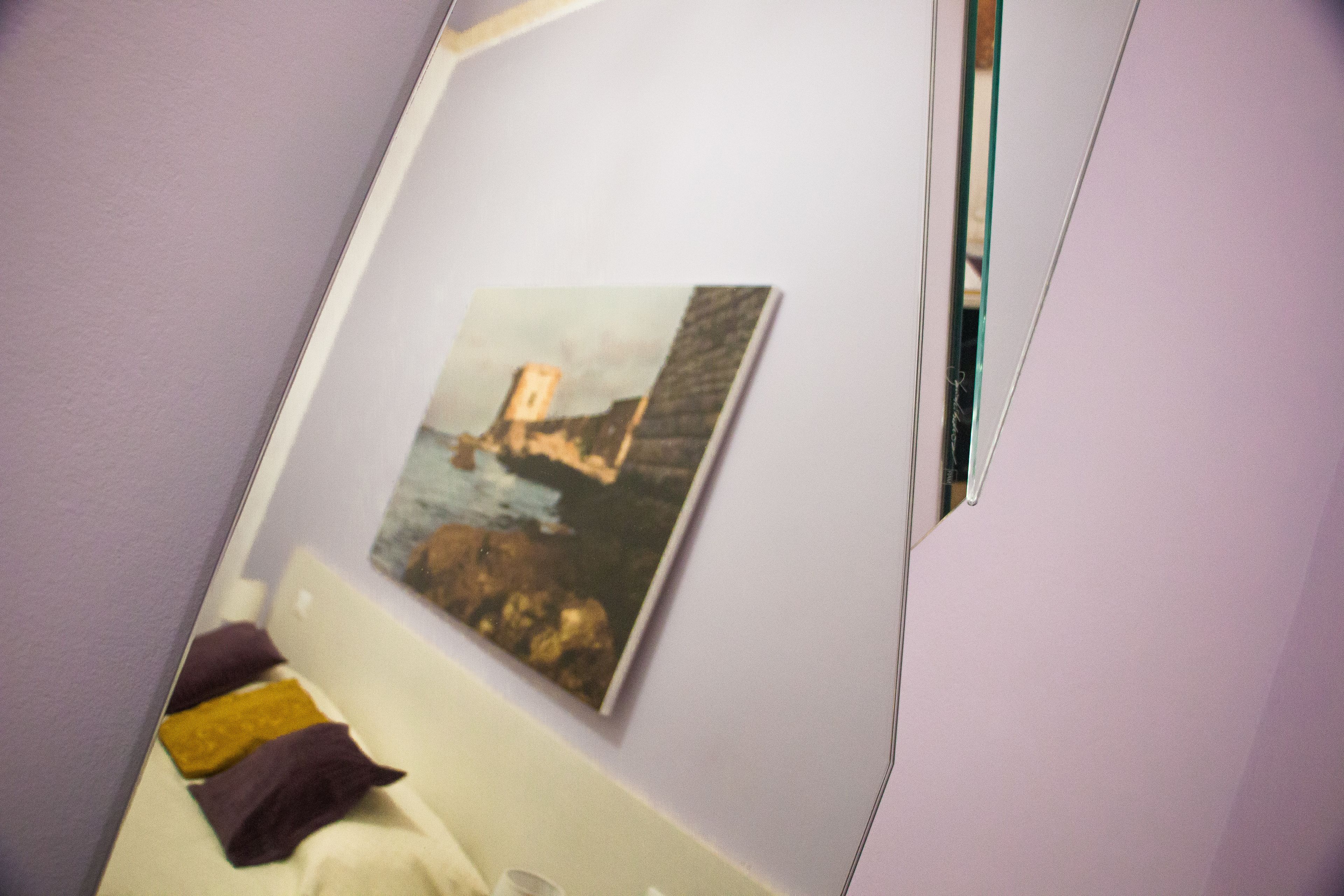 A room with a bed, a painting on the wall, and a window.