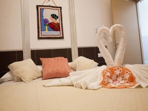 A hotel room with a bed featuring a swan-shaped towel arrangement, a framed artwork on the wall, and a window with a view. - Belle Epoque B&B (Trapani)