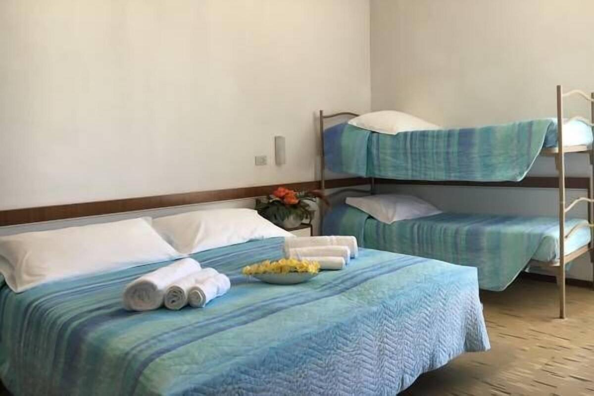 Een slaapkamer met een stapelbed, een blauwe dekbedovertrek, kussens en opgerolde handdoeken.