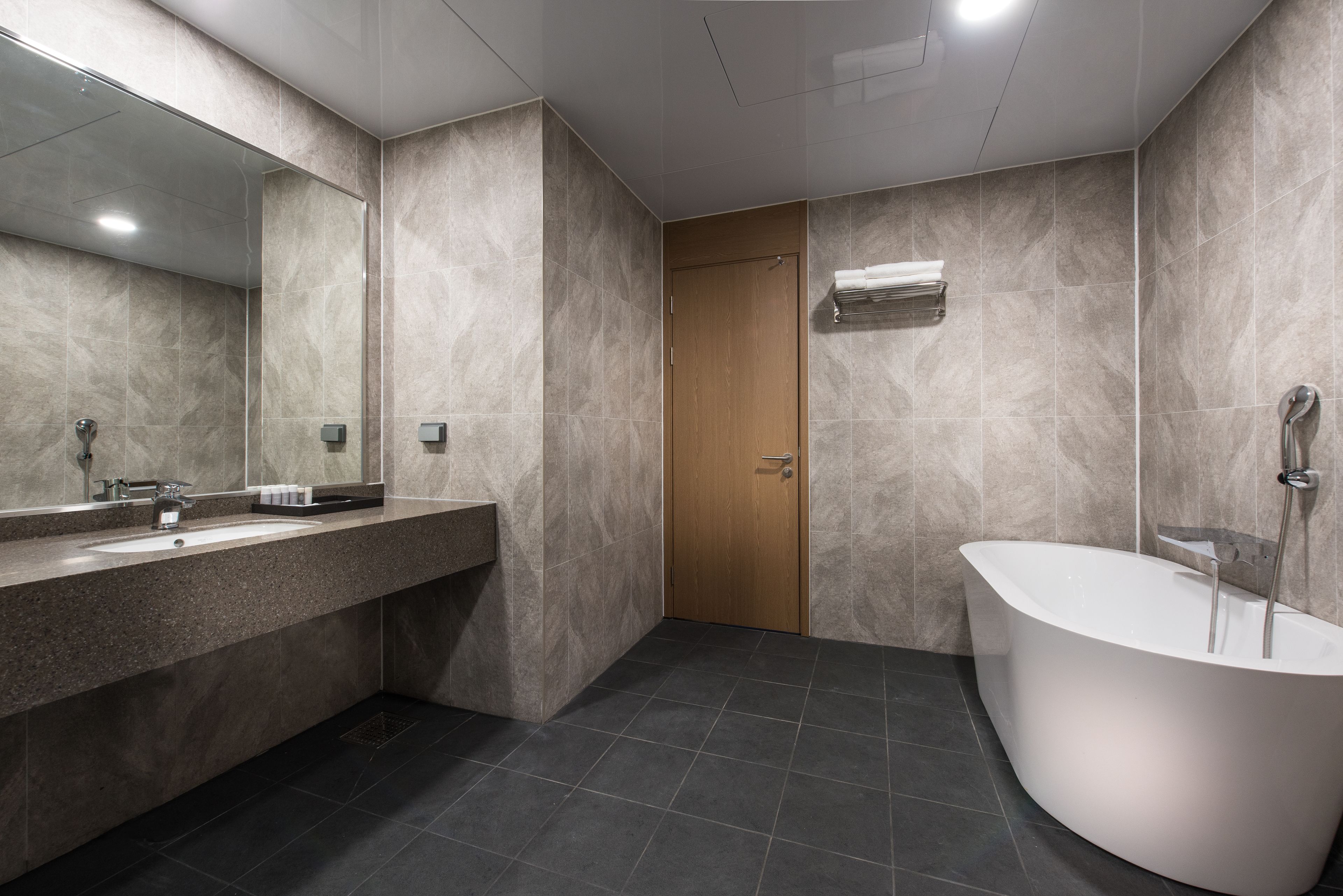 A modern bathroom with a freestanding bathtub, a large mirror, and a vanity with a sink.