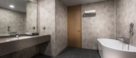 Un bagno moderno con una vasca freestanding, uno specchio grande e un mobile lavabo.