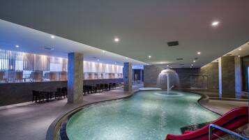 Una piscina techada, sillones reclinables de piscina