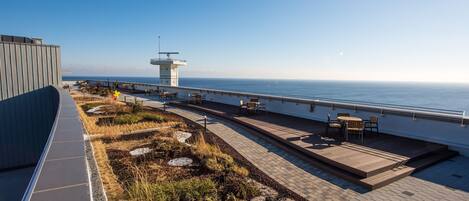 A rooftop terrace with a view of the sea, a control tower, and outdoor seating.