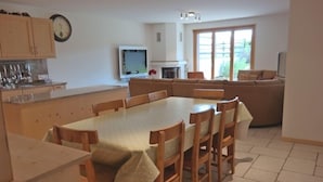A modern kitchen with a dining area, wooden cabinets, a TV, and a fireplace. - Appartement Esserts A14 (Val d'Illiez)