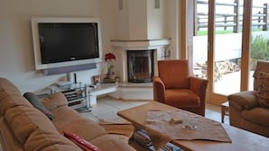 A living room with a flat-screen TV, a fireplace, and a sofa. - Appartement Esserts A14 (Val d'Illiez)