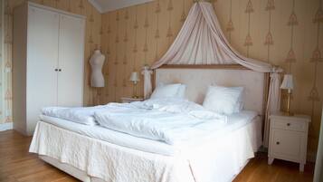 A neatly made bed with a canopy, a wardrobe, and bedside lamps in a hotel room.