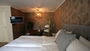 Un dormitorio con cama, televisor, bañera y candelabro.