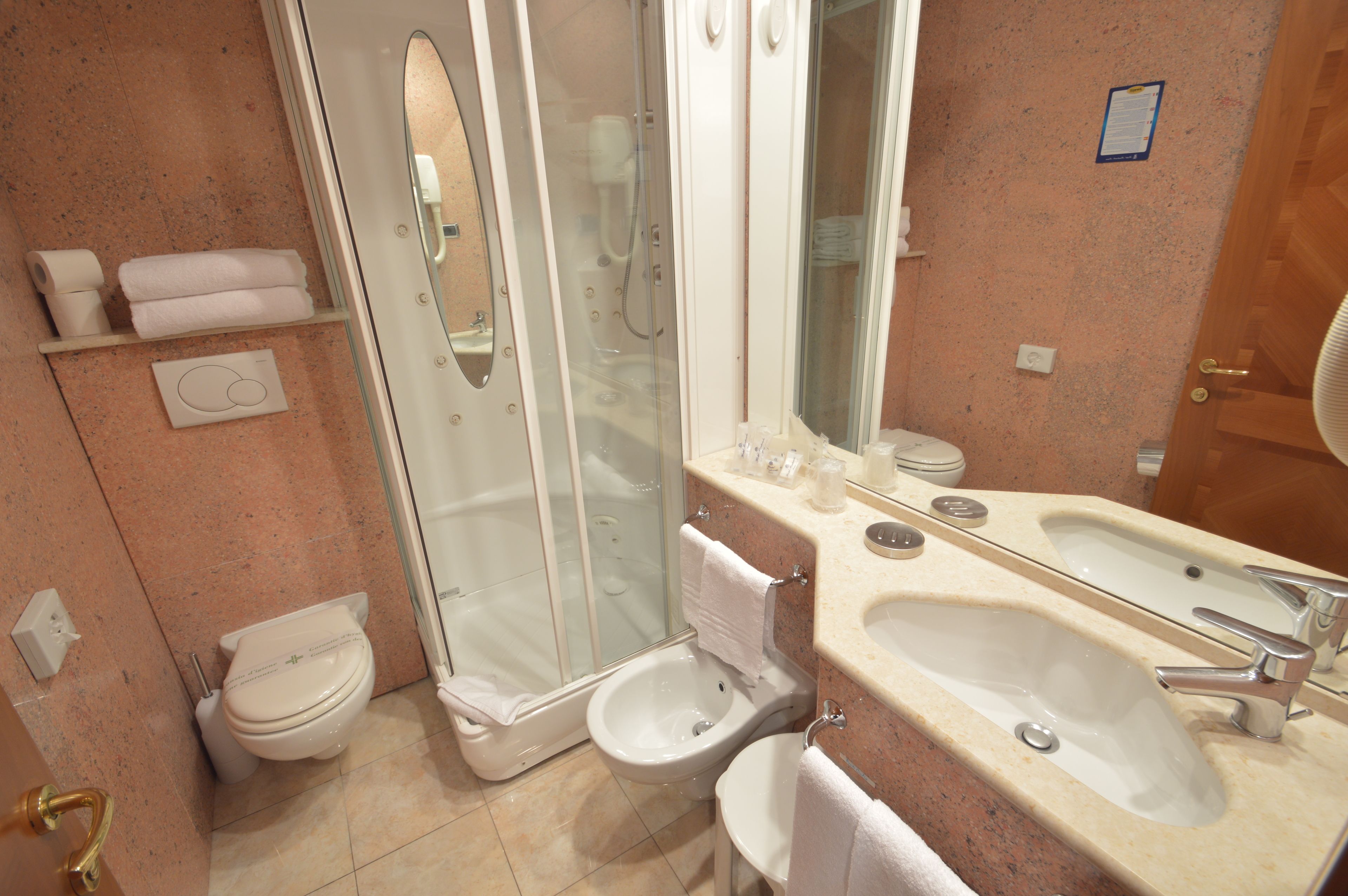 A bathroom with a toilet, bidet, and a large sink with a mirror.