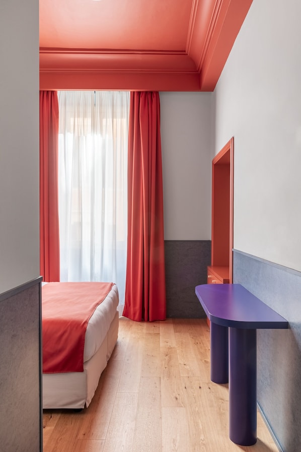 Una habitación con cama, una mesita y un espejo en la pared.