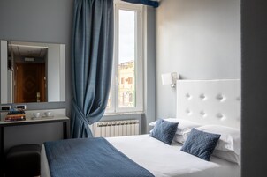 Una habitación de hotel con cama, escritorio con espejo, ventana con cortinas y radiador.