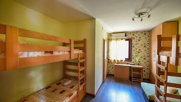 A compact room with bunk beds, a desk, and a small seating area.