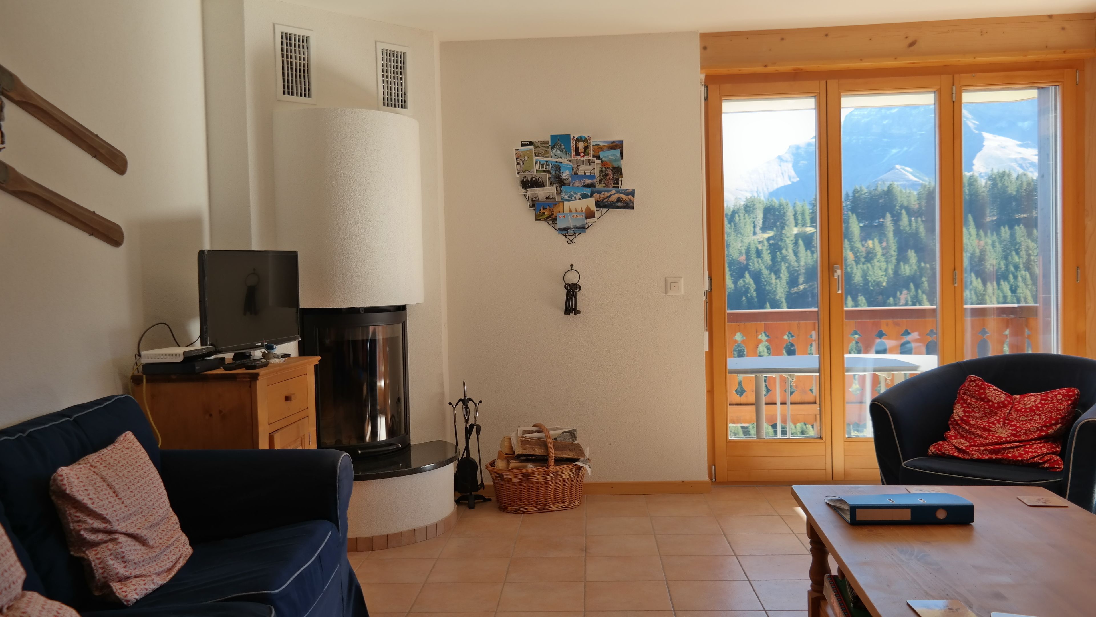 A living room with a TV, fireplace, and a view of mountains through the balcony doors.