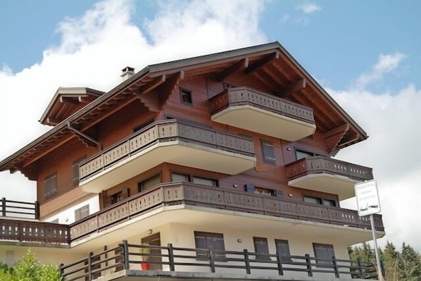 Un immeuble à plusieurs étages, doté de balcons et d’une façade en bois.