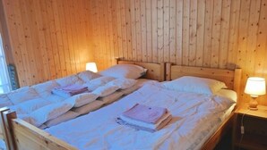 A double bed with white linens and pillows, a wooden headboard, and bedside lamps. - Appartement Myrtilles 25 (Val d'Illiez)