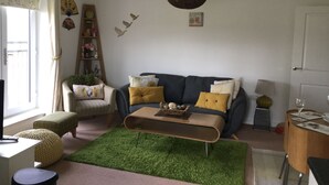 A living room with a sofa, coffee table, and a green rug. - Two Bedroom Apartment in Basildon (Basildon)