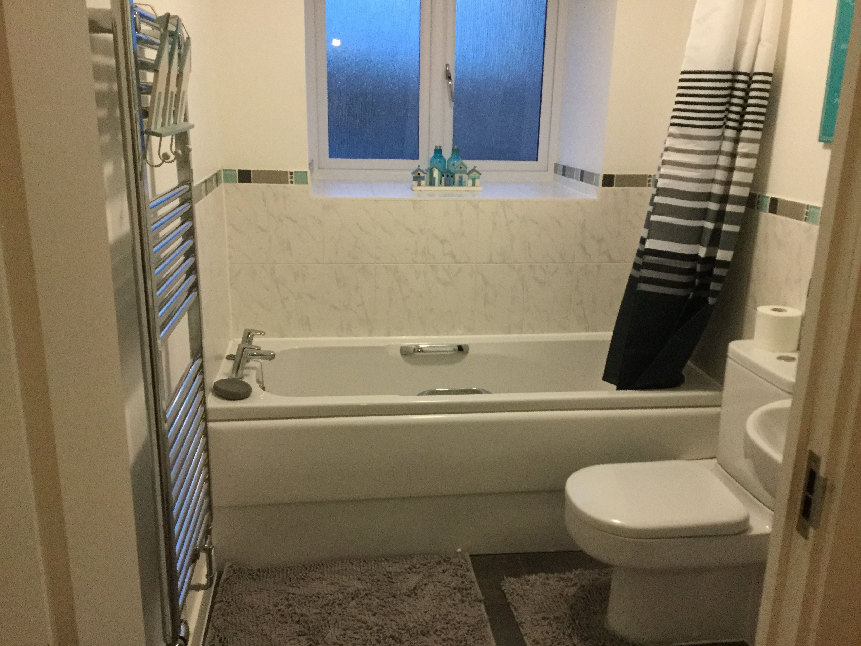 Une salle de bain avec une baignoire, des toilettes et une fenêtre au-dessus du lavabo.