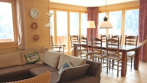 Un salon confortable avec un canapé, une table à manger et des chaises, une horloge et une fenêtre avec des rideaux.