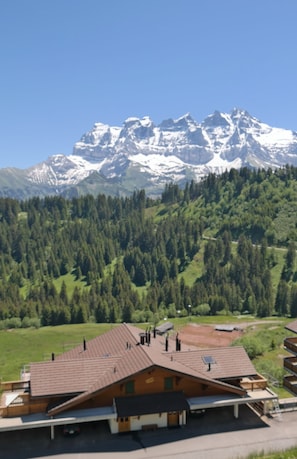 A mountain lodge with a sloped roof, a carport, and a view of snow-capped mountains.