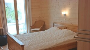 Un lit en bois dans une pièce avec une fenêtre et une chaise.