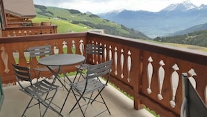 A balcony with a table and chairs, overlooking a mountainous landscape. - Appartement Esserts B40 (Val d'Illiez)