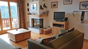 A living room with a fireplace, a television, and a sofa. - Appartement Esserts B40 (Val d'Illiez)