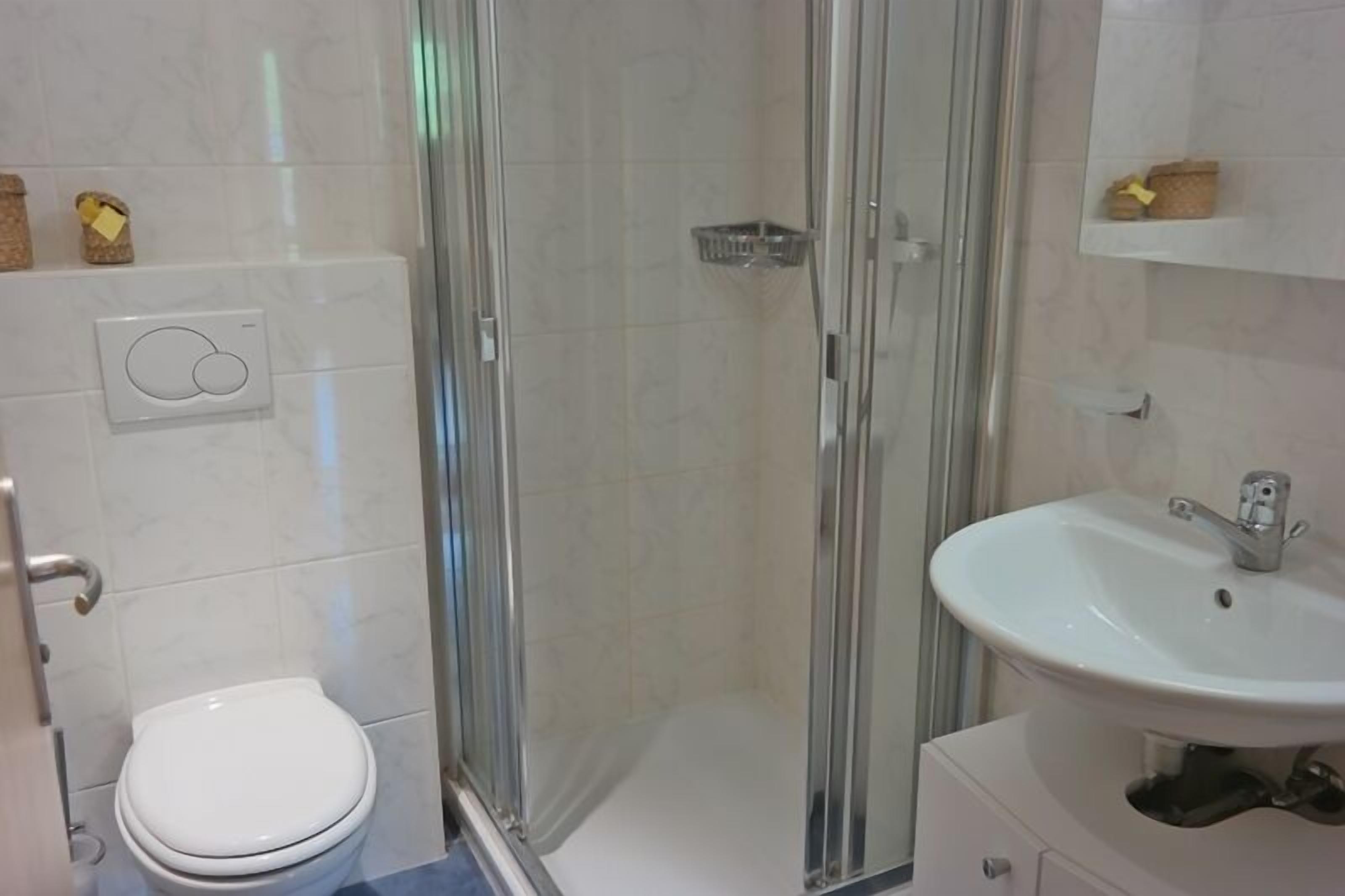 A bathroom with a toilet, a glass-enclosed shower, and a sink.