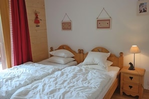 A double bed with white linens, a wooden headboard, and two bedside tables with heart-shaped drawers. - Appartement Esserts B40 (Val d'Illiez)