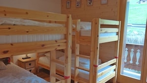 A wooden bunk bed room with a small bedside table and a window with a view of the outside. - Appartement Esserts B40 (Val d'Illiez)