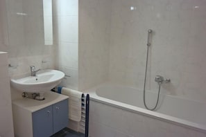 A bathroom with a white sink, a bathtub, and a shower. - Appartement Esserts B40 (Val d'Illiez)