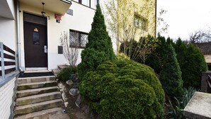 A modern building with a dark brown door, a small garden with neatly trimmed bushes, and a stone staircase leading to the entrance. - Císařka apartment (Prague)