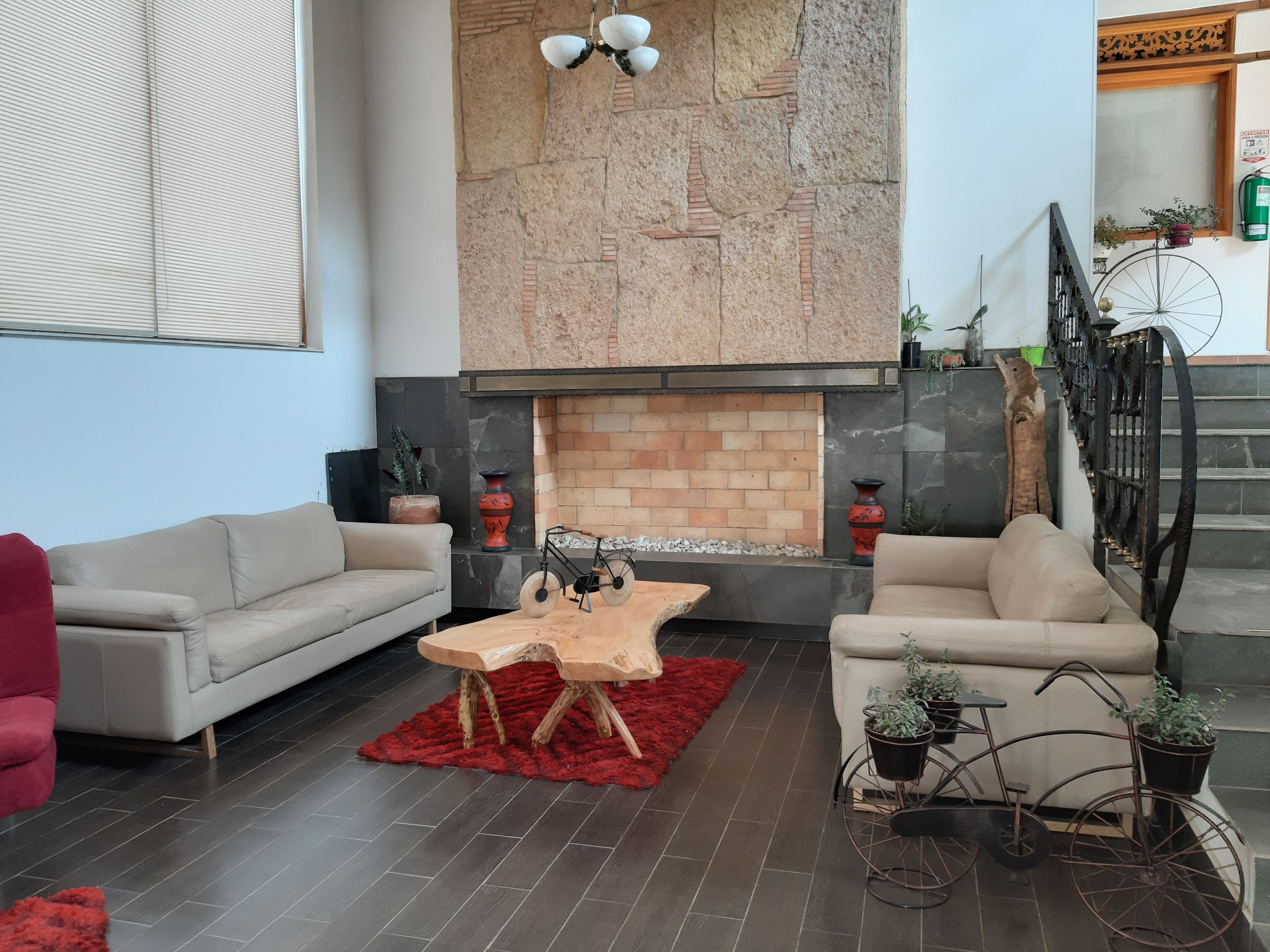 A living room with a fireplace, two sofas, a coffee table, and a red rug.
