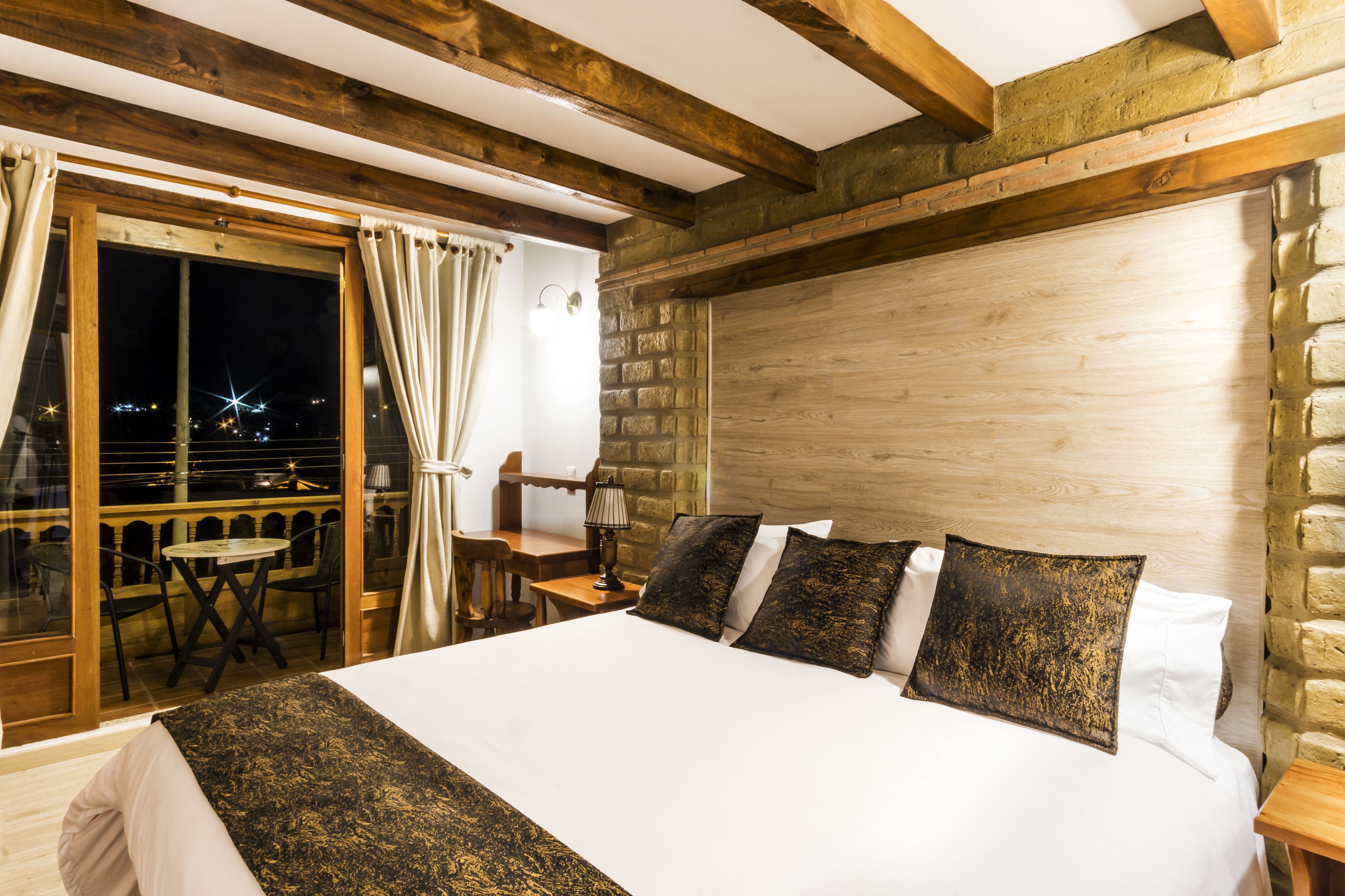 Un dormitorio con una cama grande, un cabecero de madera, una mesita de noche y una mesa con sillas.