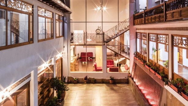 A spacious courtyard with a central staircase, potted plants, and a seating area. - Hotel El Giro (Villa de Leyva)
