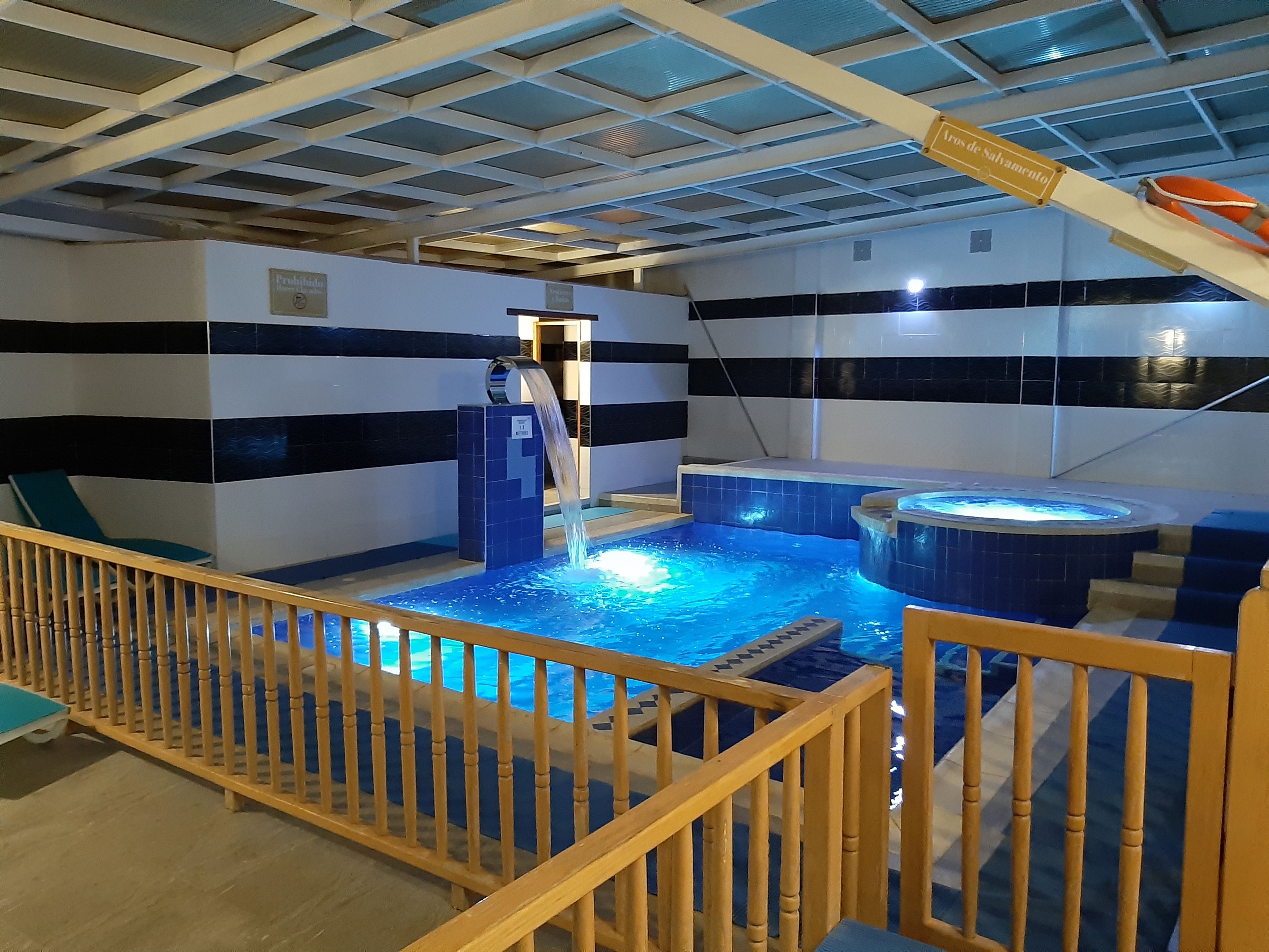 Ein Poolbereich mit Whirlpool, einer Fontäne und einer Holzterrasse.