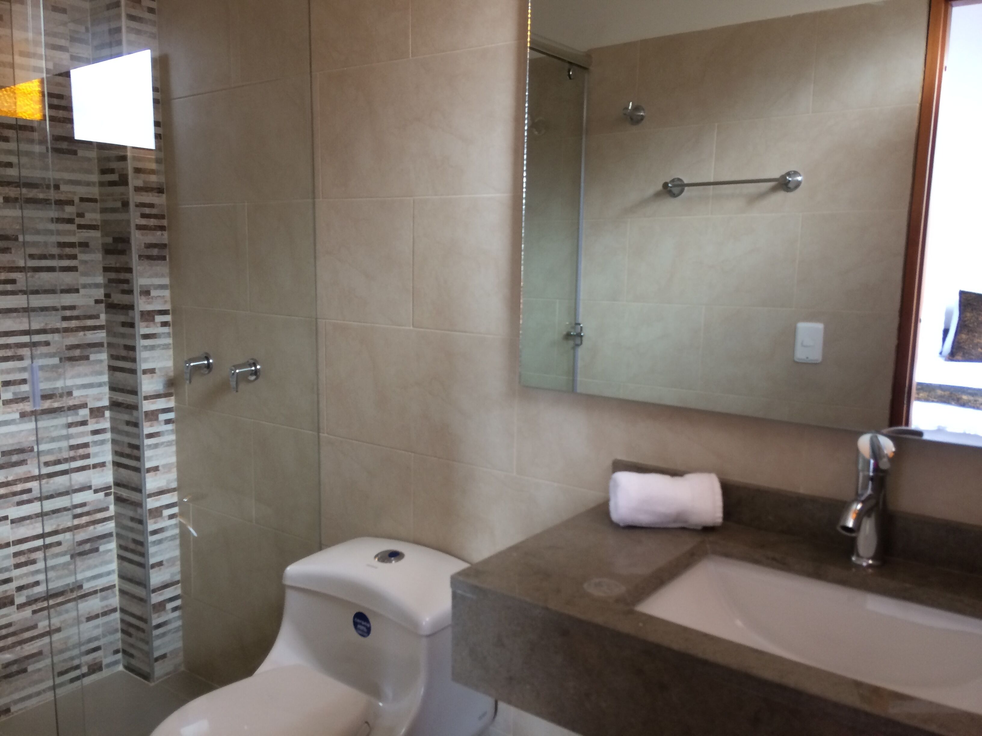 Une salle de bain équipée d’une douche, de toilettes, d’un lavabo et d’un miroir.