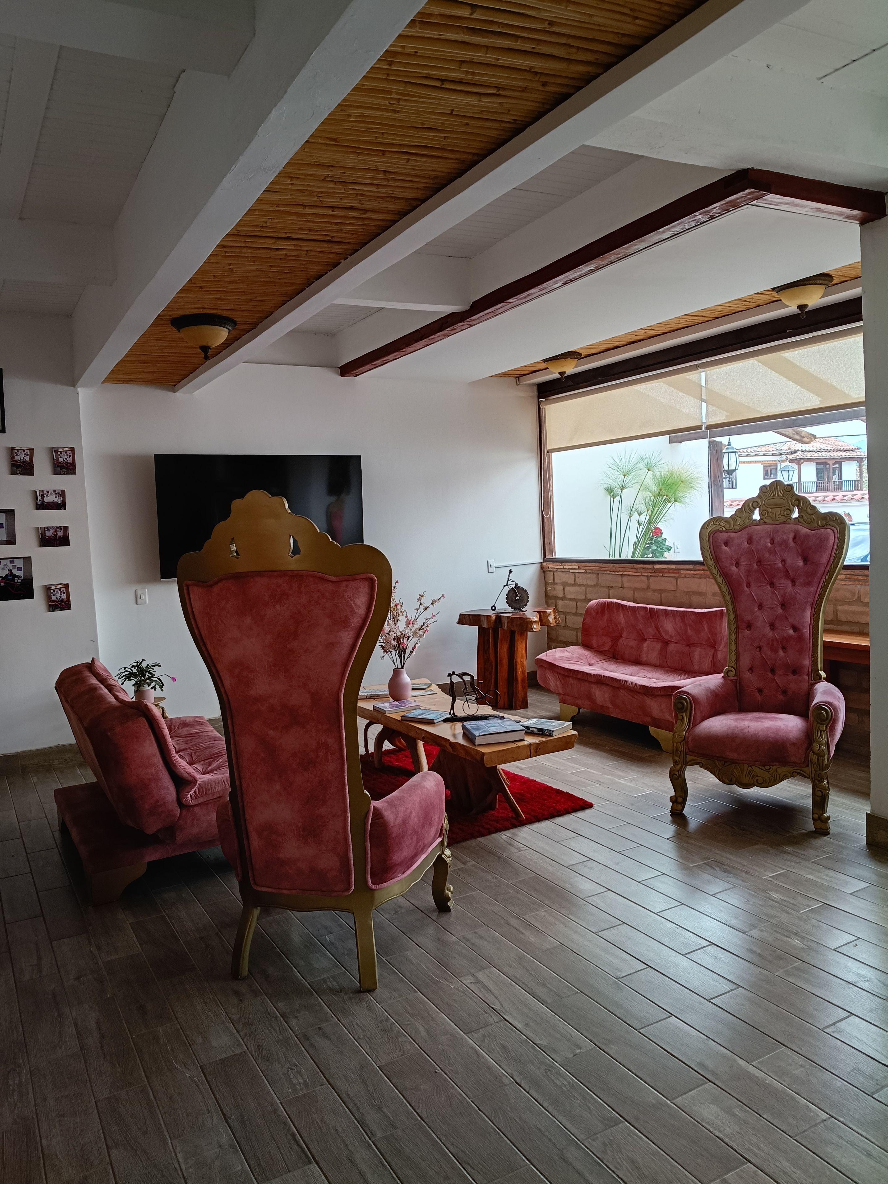 A living room with a wooden ceiling, a TV, a sofa, and two armchairs.