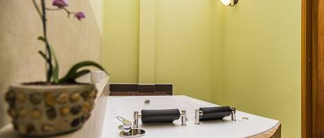 A modern bathroom with a freestanding bathtub, a potted orchid, and a wooden countertop.