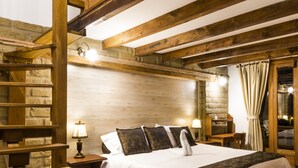 A wooden staircase leading to a loft bedroom with a bed, a desk, and a window with curtains. - Hotel El Giro (Villa de Leyva)